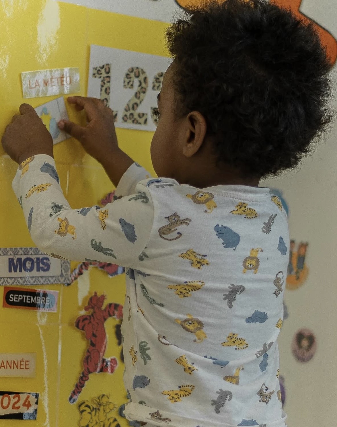 Enfant qui manipule le calendrier météo pendant le rituel du matin